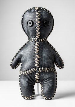 A haunting macabre doll crafted from weathered dark leather features jagged hand-stitched seams and empty black button eyes on a white base, mysterious, doll, sinister