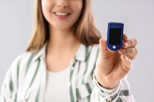 Telemedicine and health monitoring, woman holding a pulse oximeter for blood oxygen level check and respiratory wellness in a medical diagnostic context