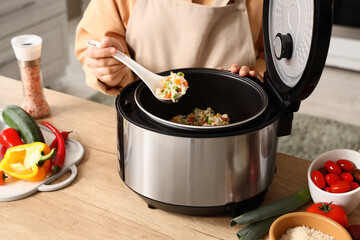 Healthy home cooking and meal preparation, person serving vegetable rice from a modern electric...