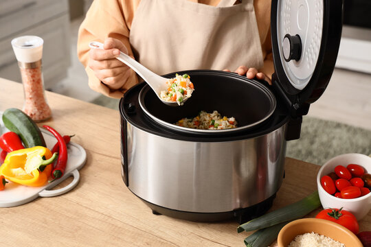 Healthy home cooking and meal preparation, person serving vegetable rice from a modern electric rice cooker in a kitchen for nutrition and diet