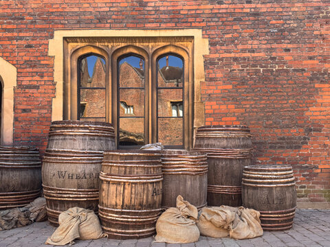 Medieval Wooden Barrels and Hessian Sacks by a Tudor Brick Wall with Stone Window