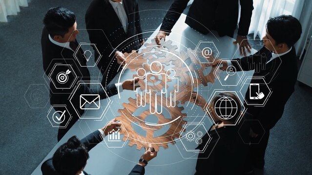 A group of professionals collaborates over a large gear mechanism, surrounded by digital icons symbolizing innovation, strategy, and modern workplace dynamics. Raster