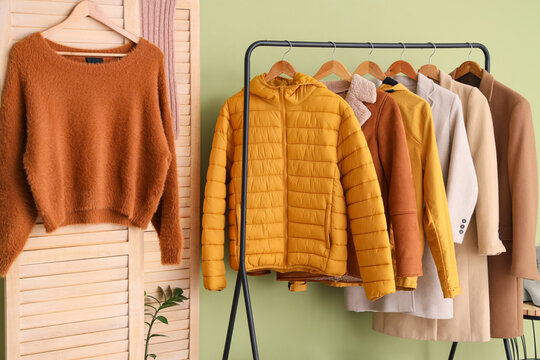 Rack with stylish warm clothes and folding screen in interior of dressing room