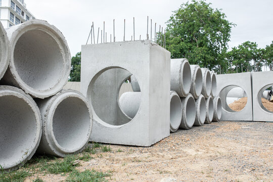 Square concrete culvert block section rests on dirt ground at construction site, drainage material staged and waiting installation, supplies prepared ahead of storm water system work