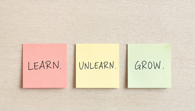 Learn unlearn grow concept on colorful sticky notes arranged on wooden surface for personal development and mindset change