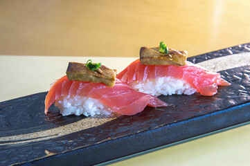 Gourmet salmon nigiri with foie gras on black plate © PhamThi