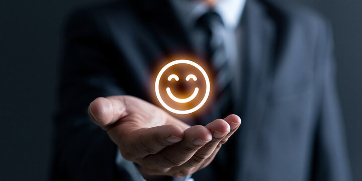 A businessman holding out his hand with a glowing smiley face icon above it, symbolizing happiness and satisfaction