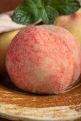 Ripe flat peaches with fresh mint on rustic plate © TranVan