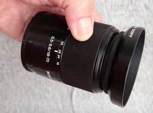 Hand holding Sony camera lens for photography