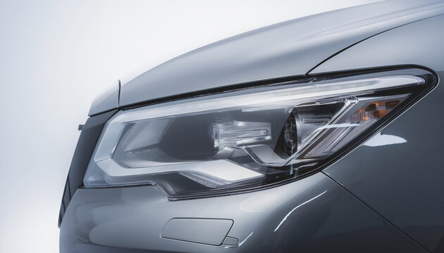 Close-up detail of a modern silver luxury car front headlight assembly featuring sleek LED technology and refined aerodynamic body contours