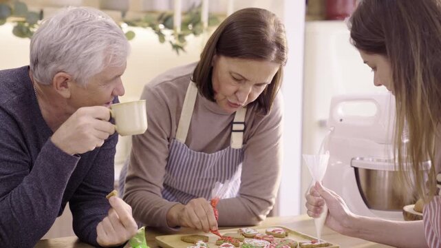 Family decorating Christmas gingerbread cookies together at home
