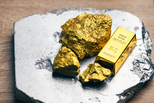 pure gold bullion bar 99.9 next to natural gold nuggets on a silver ore stone plate as a conceptual backdrop for global finance gold investment wealth safety haven banking economy and asset management