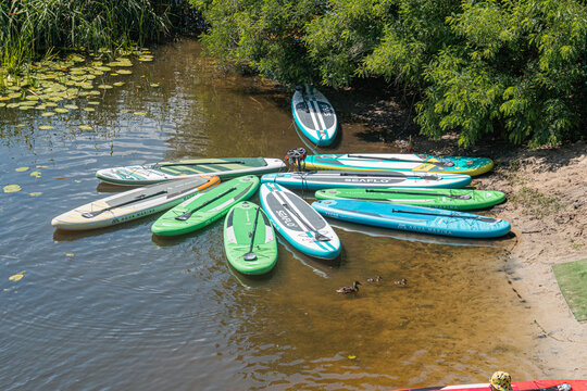 Several colorful kayaks and canoes arranged in a semi-circle on calm, natural or parklike waters Boats vary in shades of blue, green, white, and appear well maintai - Kyiv, Ukraine 07-12-2025
