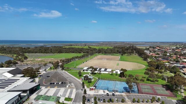 Aerial view of local sports facilities, sports ovals, tennis courts, and community infrastructure adjacent to residential housing and coastal wetlands in Altona Meadows, Victoria, Melbourne Australia