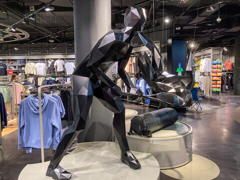 Indoor retail space featuring a large, dynamic sculpture of an athletic figure in a shopping mall or department store TSUM Kiev The sculpture is monochromatic, text - Kyiv, Ukraine 07-13-2025