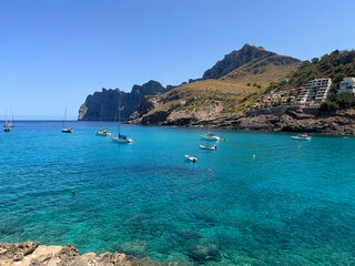 Obraz premium View over Cala Sant Vicenç, in the municipality of Pollença, on the island of Mallorca, Balearic Islands, Spain, showing small boats anchored in the turquoise bay beneath a rocky headland.