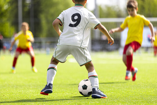Junior Soccer Player in Number 9 White Jersey Controlling Ball During Match - Youth Football Game Action on Sunny Grass Field