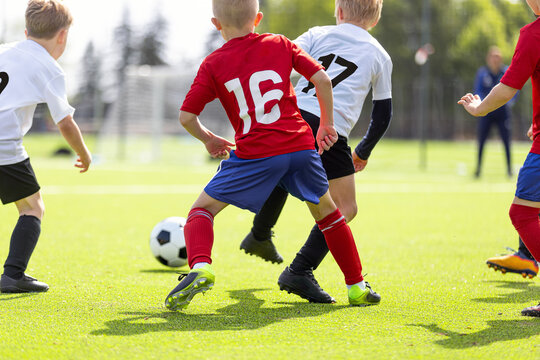 Junior Soccer Player in Red Jersey Number 16 Dribbling Ball Past Opponents in White Kits - Youth Football Tournament Match Action on Grass Field