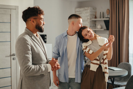 Real estate agent meeting young couple receiving new house keys