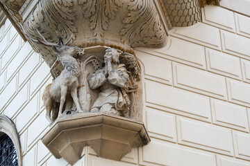 Stone corbel relief sculpture of a stag and kneeling hunter on a building facade © Pavel Jiranek