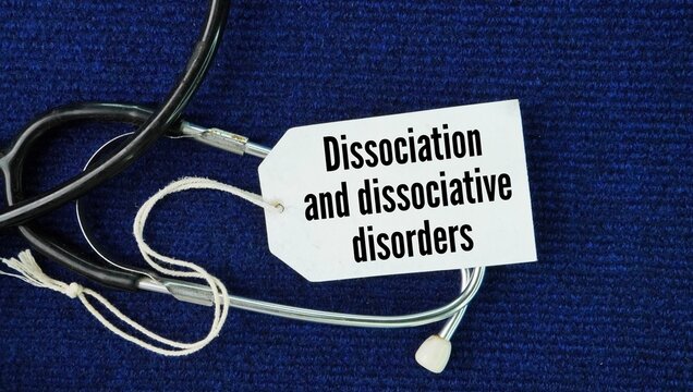 Stethoscope and paper tag with the words Dissociation and dissociative disorders. mental process that causes a disconnection between a person's thoughts, memory, surroundings, actions