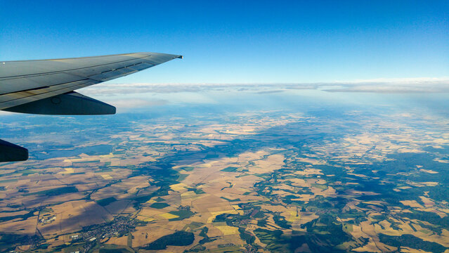 Aerial view of patchwork farm fields seen below an airplane wing over the Czech Republic