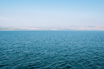 Fototapeta premium Calm blue water of the Sea of Galilee stretching beneath hazy hills in Israel