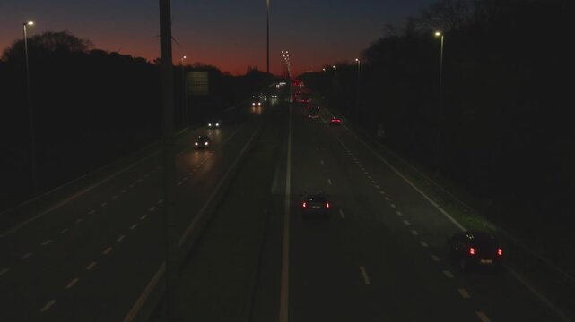 Aerial view of highway traffic at night with a colorful twilight sky.