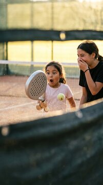 Girl reacts with surprise while supportive woman encourages her courtside. Concept of parent support, beginner sports and positive coaching.