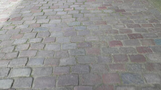POV shot moving forward over a historic European cobblestone street. First-person perspective of walking on an old stone pavement.