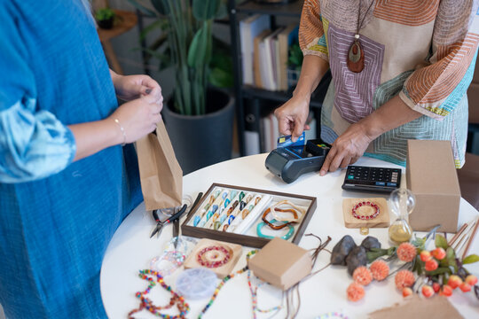 woman tapping credit card on EDC terminal for secure cashless payment in handmade shop using contactless card payment cashless society financial technology