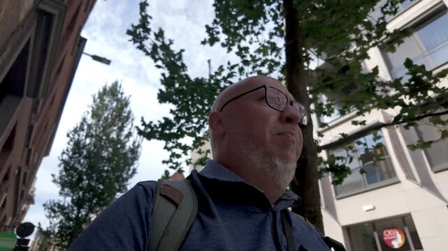September 03, 2026 - Thoughtful Mature Man with Glasses Walking and Sightseeing in an Urban Environment