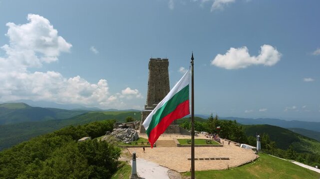 Aerial view Bulgarian flag waving with Shipka Monument Liberty in background blue sky green mountain landscape Bulgaria travel destination historical national symbol drone