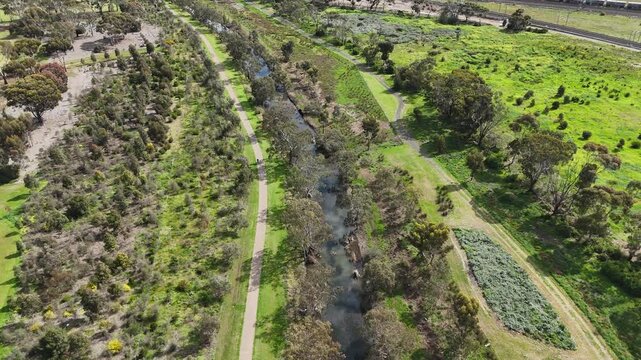Aerial&nbsp;view of narrow waterway of Laverton Creek surrounded by native bushland, walking trails, and open parkland in Altona Meadows, Melbourne Australia. Riparian corridor, environmental conservation 