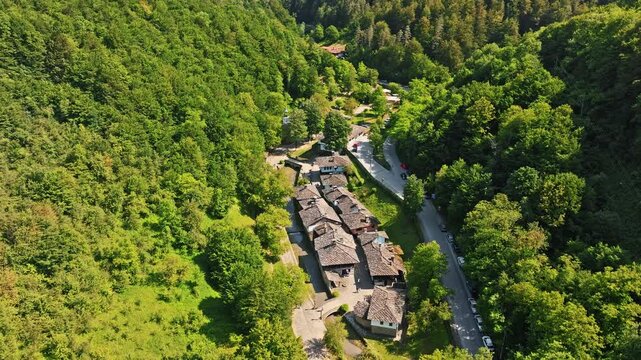 Aerial view Etar Regional Ethnographic Open Air Museum traditional stone tile houses surrounded by dense forest Gabrovo Bulgaria travel destination culture heritage drone