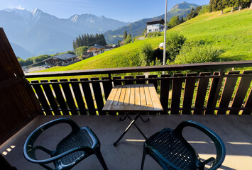 Obraz premium cozy wooden balcony with comfortable lounge chair overlooking scenic green mountains