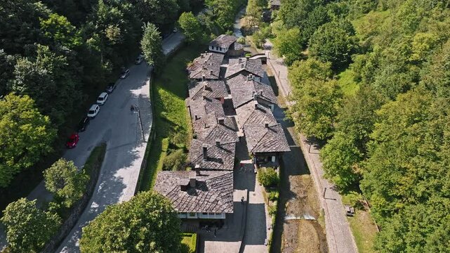 Aerial view Etar Open Air Museum street traditional stone houses river valley forest green trees Gabrovo Bulgaria travel culture heritage tourism destination drone video footage