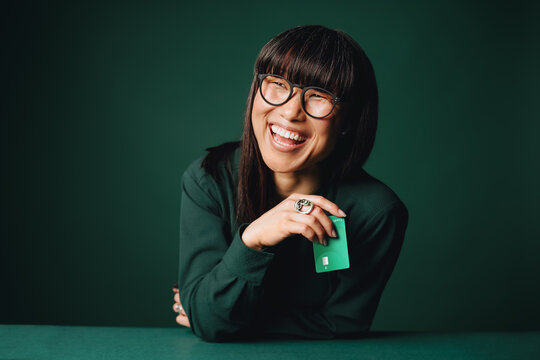 Mature woman laughing with bank card for exclusive membership in studio