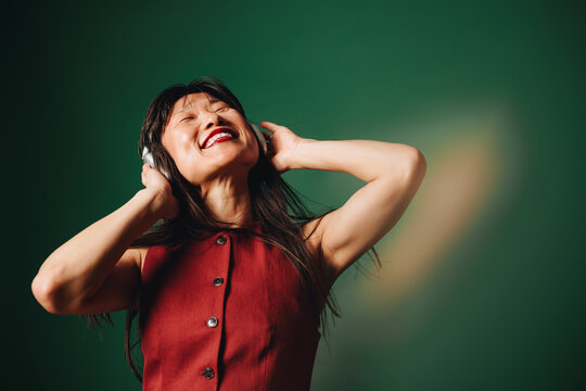 Woman wearing headphones listening to music in studio portrait