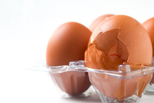 a cracked chicken egg in plastic packaging isolated on a white background