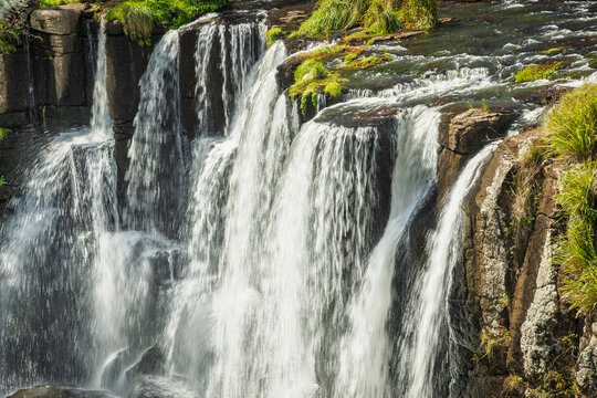 Water cascades over the top section of Upper Ebor Falls, a striking waterfall flowing over basalt rock columns on the Guy Fawkes River along the Waterfall Way at Ebor in New South Wales, Australia.