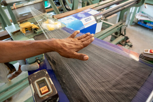 Worker's hand smoothing silk threads on a weaving loom, Dhaka Division, Dhaka, Bangladesh