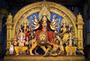Obraz premium Colorful Hindu goddess Durga statue with lion and deities in ornate golden temple setting