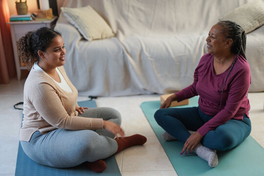 African mother and daughter doing yoga class at home during winter season - Sport, active lifestyle and family bonding concept - UGC content