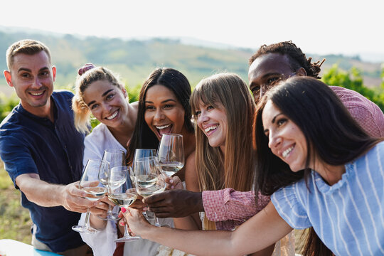 Happy diverse friends celebrating and cheering during wine tasting while taking a photo together - Multiracial people, party and vacation concept - UGC content