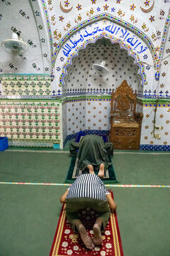 Two men prostrating in prayer before the ornate mosaic mihrab of Tara Masjid, Dhaka Division, Dhaka, Bangladesh