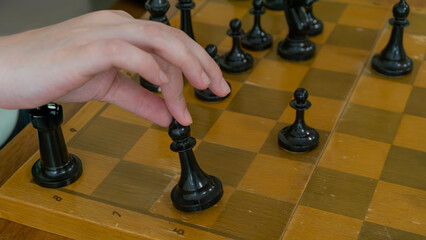Person hand moving black pawn piece on old scratched wooden chessboard under daylight © Rodion