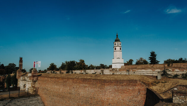A wide view shows the Sahat Kula clock tower and historic ramparts of Belgrade Fortress. Serbia tourism, military heritage and city travel concept.