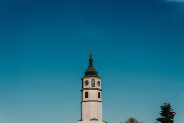 Fototapeta premium The Sahat Kula clock tower rises above Belgrade Fortress against a clear blue sky. Historic architecture for Serbia tourism, heritage and travel content.