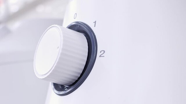Man Turning Control Knob on Home Appliance. Close-up of a hand adjusting a household device setting. Concept of temperature control, operation, convenience and home technology.
